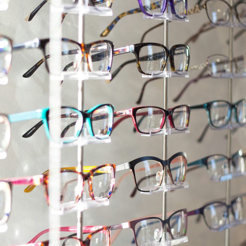 several rows of different coloured eye glasses at optometry clinic